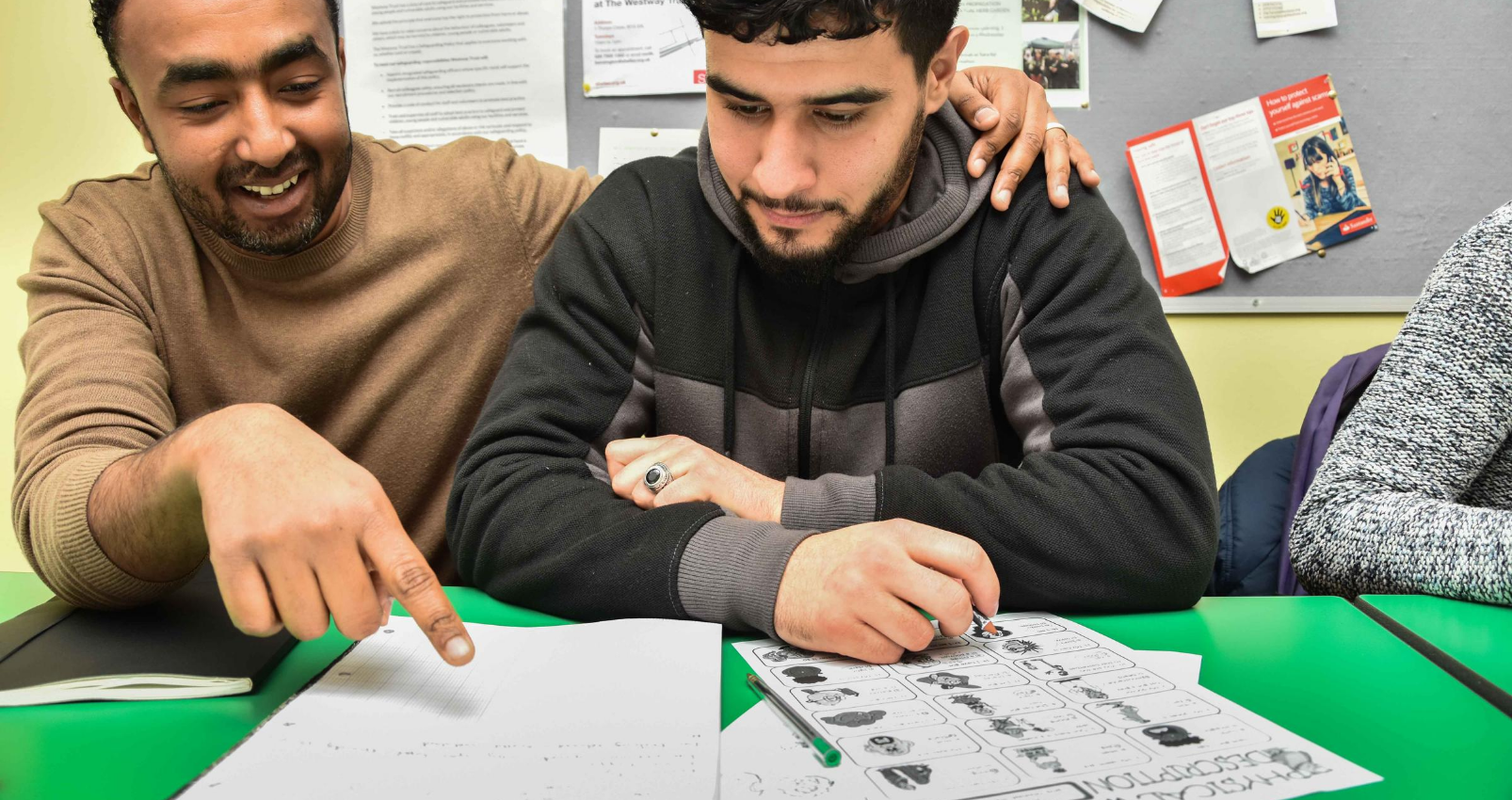Teaching assistant helping a student with their worksheet at their desk