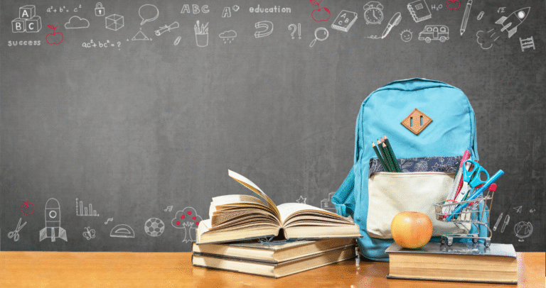 Image of school books and a backpack on a desk in front of a chalk board