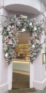 a photo of a flower arch on a door to a shop