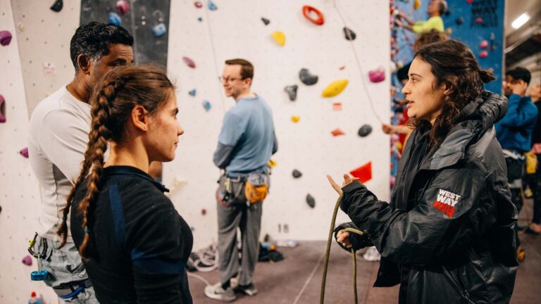 Instructor speaking to young pair at climbing wall at Westway Sports Centre