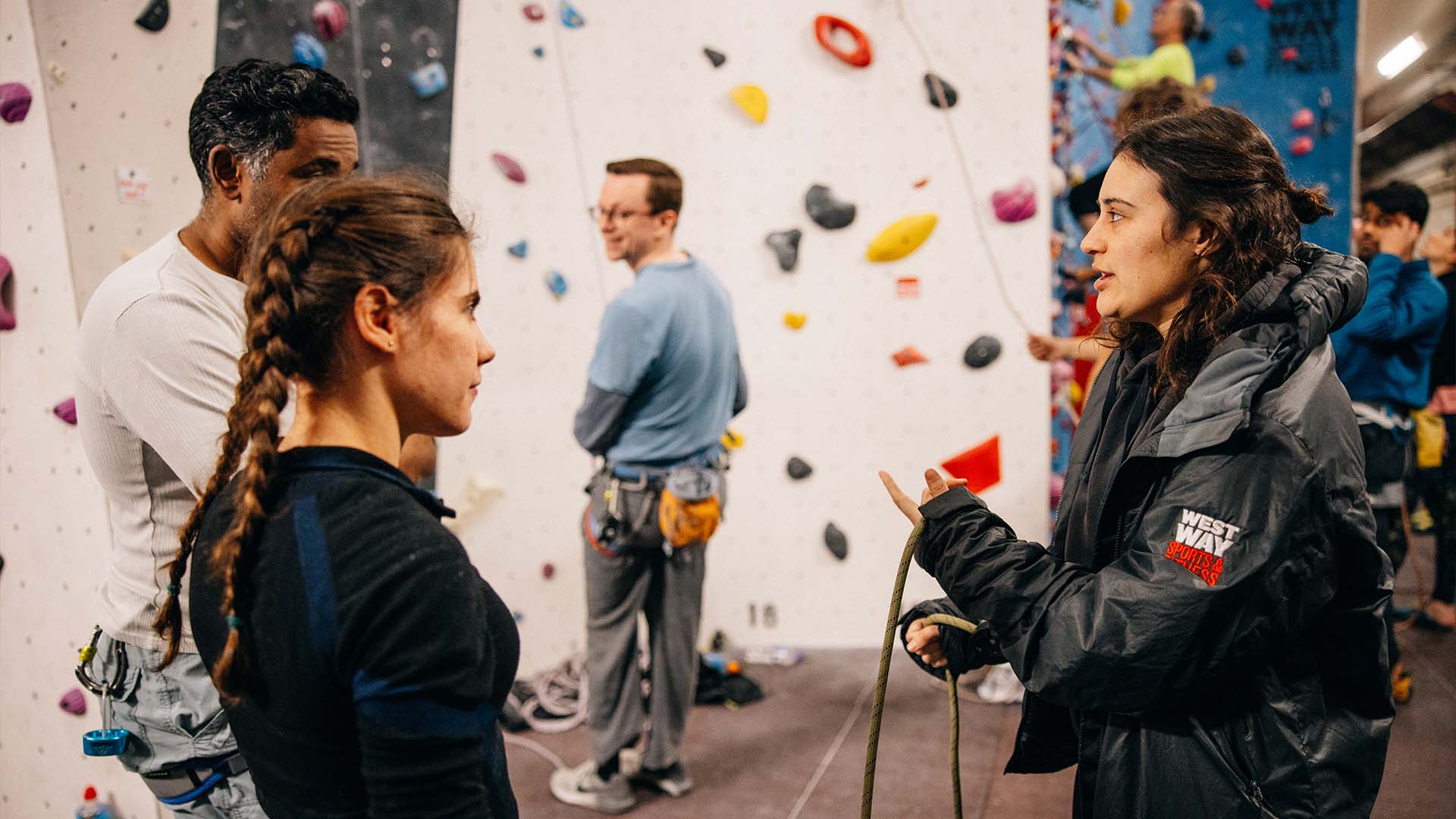 Instructor speaking to young pair at climbing wall at Westway Sports Centre